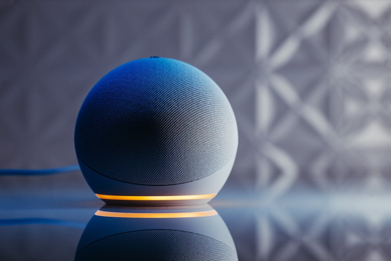 Close-up of a modern smart speaker in a stylish setting with illuminated base and reflection.