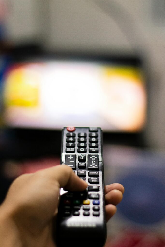 pexels photo 3721597 3721597 Close-up of a hand holding a remote control, watching TV indoors. Captures modern leisure and technology.